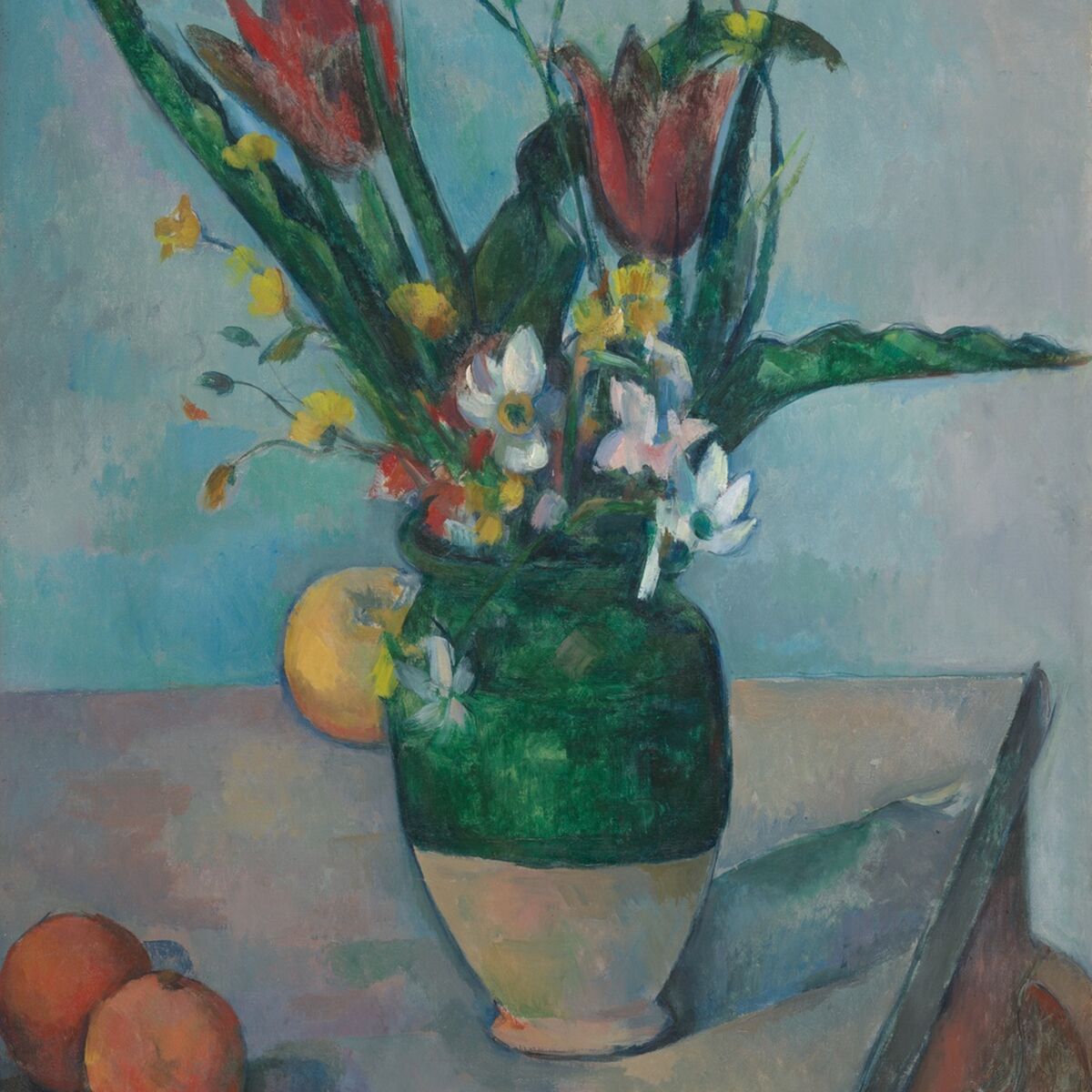 Still-life painting of a green vase holding red tulips and small white and yellow flowers on a table beside two oranges.